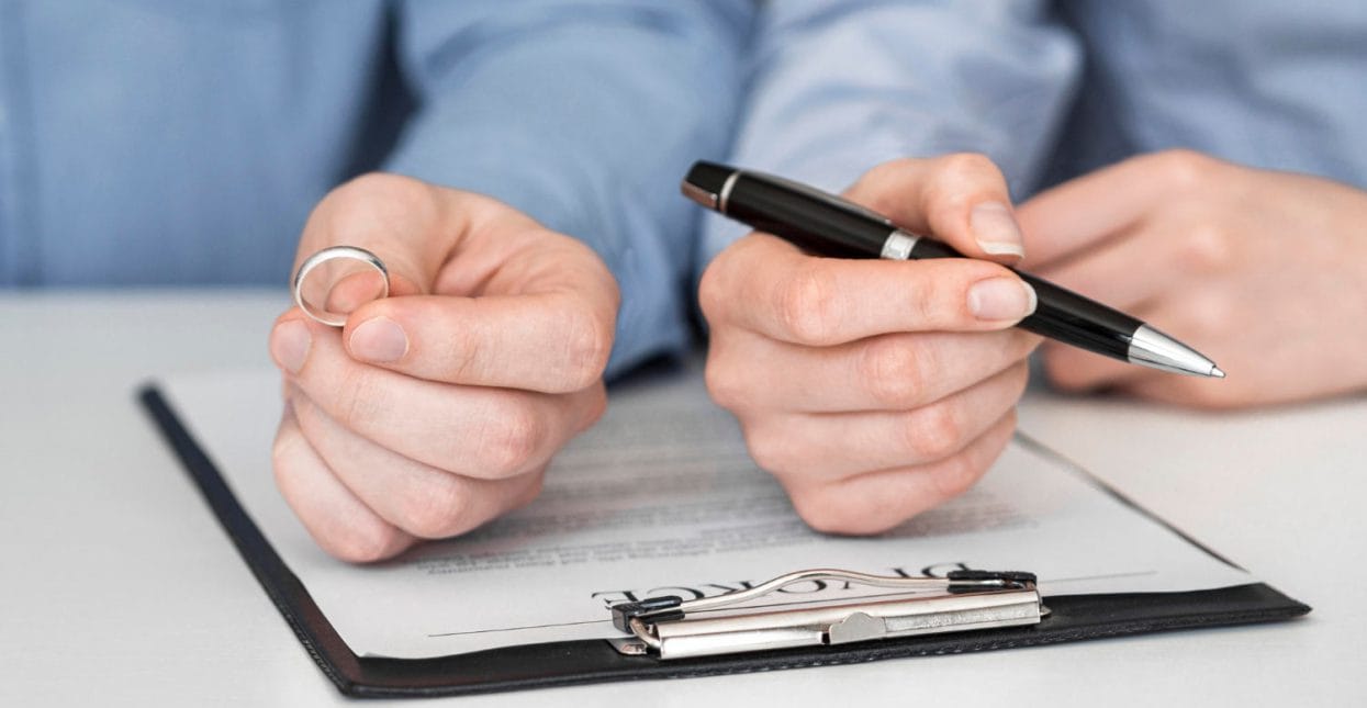 common-law partner holding marriage ring over certificate paperwork